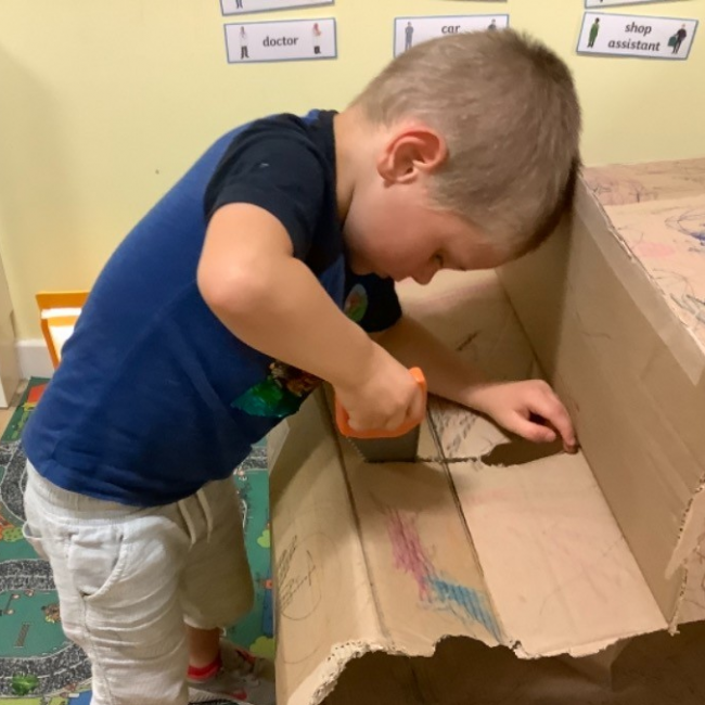 A boy cutting cardboard 