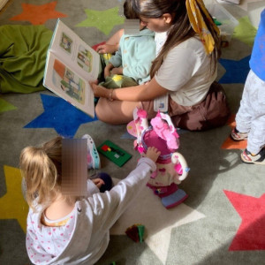 Children reading a book with their teacher 