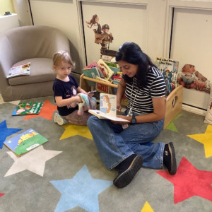 A child reading a book with a teacher 