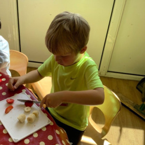 A child cutting up fruit. 