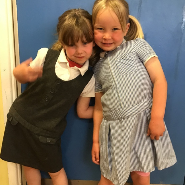 Two girls trying on school uniform. 